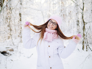 Wall Mural - Adorable happy young blonde woman in pink knitted hat scarf having fun strolling snowy winter forest in nature