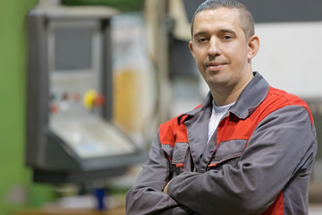 Service man worker with folded arms at factory workshop background