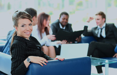 Wall Mural - Closeup of a pretty young businesswoman smiling in a meeting with her colleagues in background.