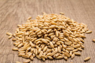 Oat cereal grain. Pile of grains on the wooden table. Selective focus.