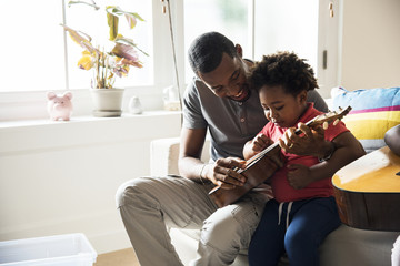 Wall Mural - African father teaching son how to play guitar