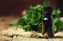 Essential Oil Of Peppermint In A Small Brown Bottle With Fresh Green Mint, Rustic Style, Vintage Wooden Background, Selective Focus