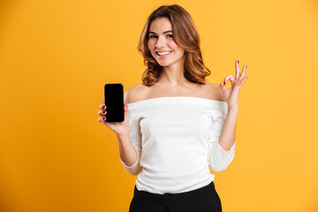 Canvas Print - Smiling young woman showing display of mobile phone.