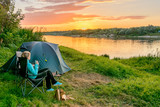 Fototapeta Most - Young woman in camping with a tourist tent on the river bank. Russia.