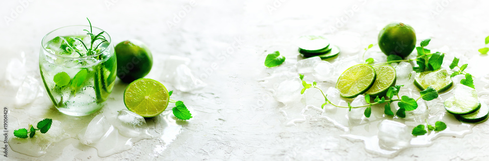 Homemade lime lemonade with cucumber, rosemary and ice, white background. Cold beverage, detox water. Copyspace. Banner - obrazy, fototapety, plakaty 