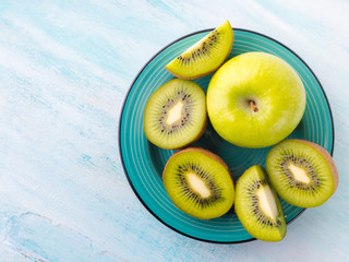 Green apples and kiwi on turquoise background