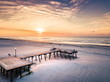 Sunrise over the beach and wooden dock aerial view
