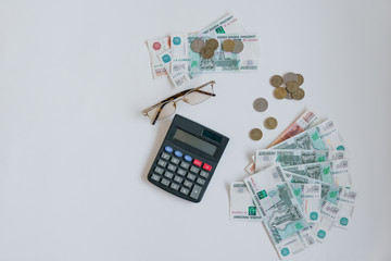 Money in Russia. Banknotes five and one thousand rubles, background, selective focus, on the table, glasses and a calculator. different coins.