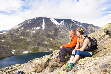 Wall Mural - Sport couple hiking on Besseggen. Hikers enjoy beautiful lake and good weather in Norway.