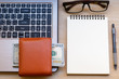© THAWEERAT - workspace with wallet, banknotes, laptop, eyeglass, notebook and pen on wooden table.