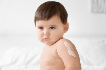 Wall Mural - Cute baby with body cream on arm against light background