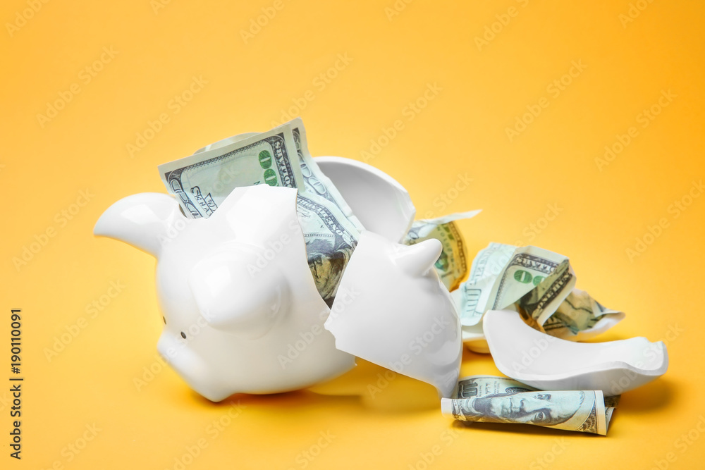 Broken piggy bank with money on color background