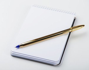 Wall Mural - Notepad with blank paper next to golden ball pen on white background. Isolated. Mockup.