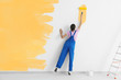 © Africa Studio - Young female decorator painting wall in room