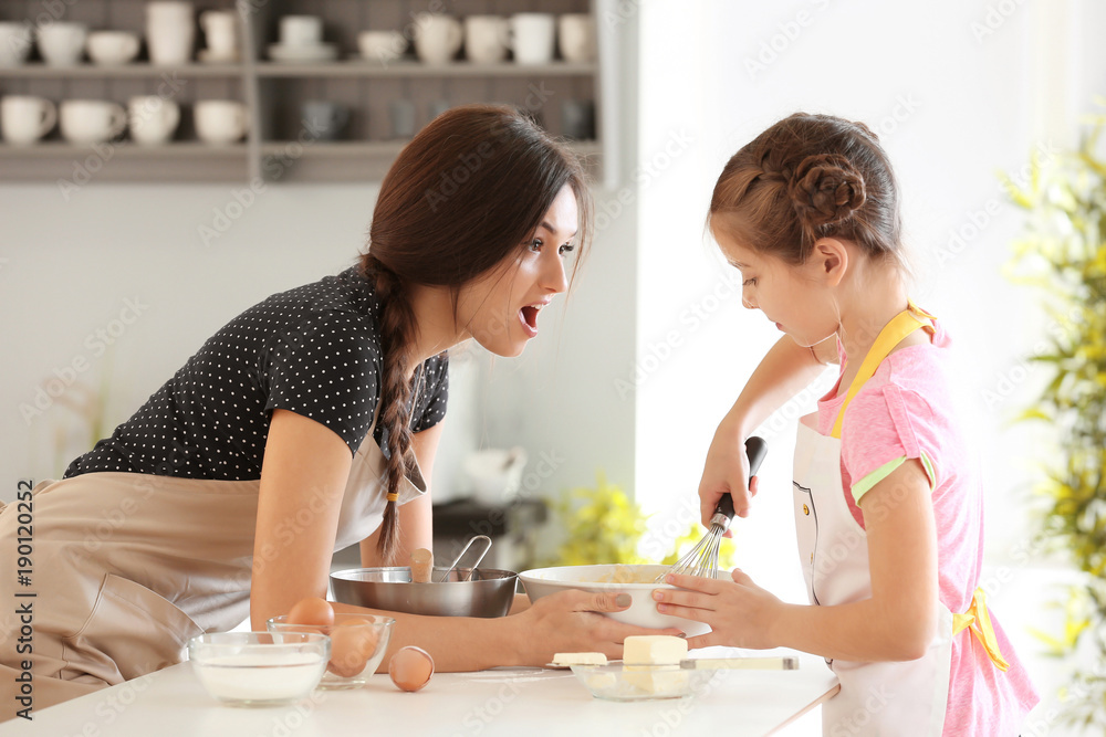 Mother and daughter preparing dough indoors