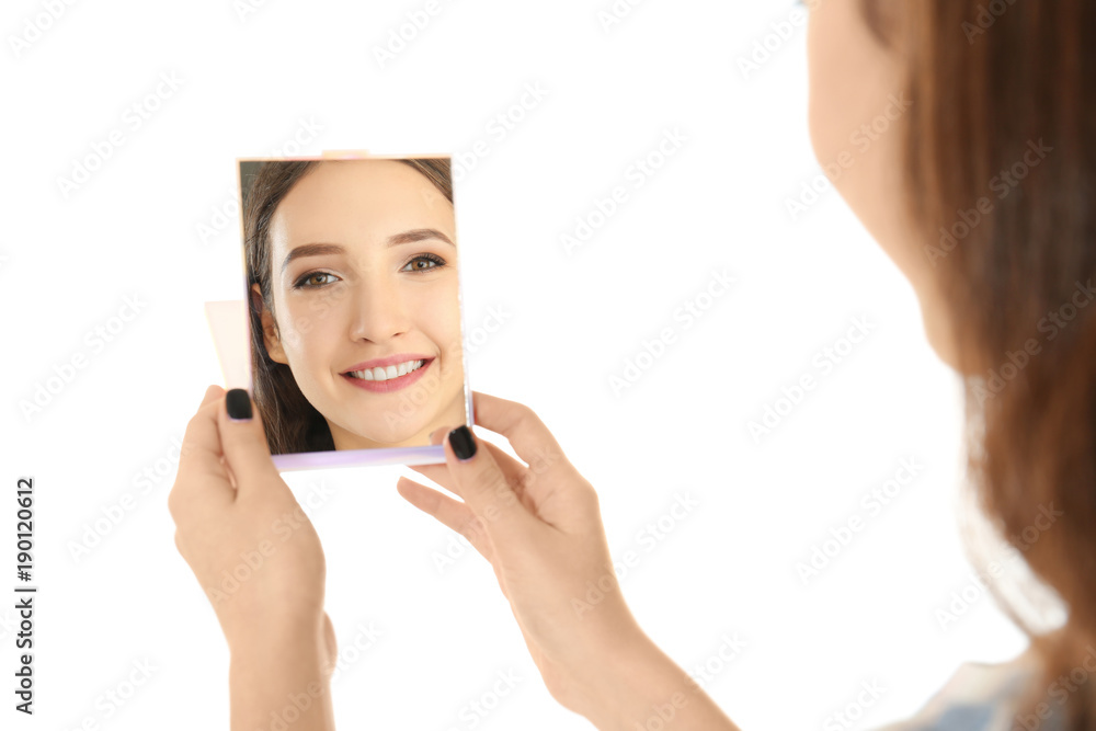 Young pretty girl looking in mirror on white background