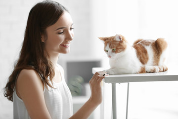 Beautiful young woman with cute cat at home