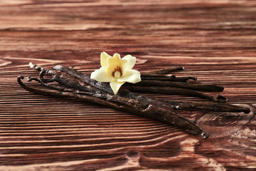 Wall Mural - Vanilla sticks and flower on wooden background