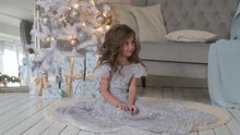 The Girl Is Sitting In A Beautiful Shiny Dress. Christmas Interior