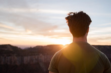 A Man Standing, Looking Out At The Grand Canyon During Sunset. 