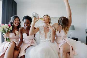 Bride and bridesmaids enjoying before wedding in hotel room