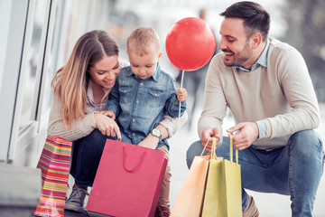 Happy family with little son and shopping bags in city