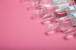 Ampoules with hyaluronic acid, botox and collagen on a pink background, empty space for text.