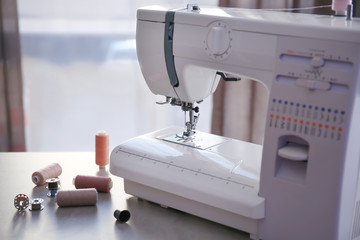 Poster - Modern sewing machine with threads on table