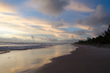 Fototapeta Morze - view of the blue sky and full of morning clouds on a beach with sea water reaching in the sand.