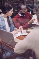 Good call. Pensive concentrated two colleagues gazing at diagram while sitting at cafe and using pencils