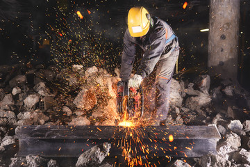 construction worker cutting an iron beam.