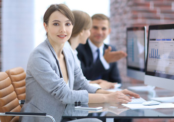 Poster - young business woman sitting at the Desk