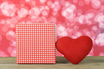 Wall Mural - Red heart and Gift Box placed on a wooden floor on a red bokeh background.