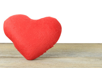 Red heart placed on a wooden floor on a white background.