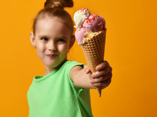 Pretty baby girl kid eating licking banana and strawberry ice cream in waffles cone