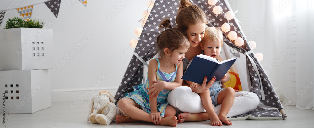 family mother reading to children book in tent at home - obrazy, fototapety, plakaty 