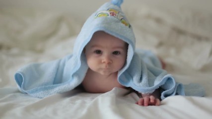 Canvas Print - Cute little baby boy, relaxing in bed after bath, smiling happily