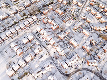Aerial View Of Snow Covered Traditional Housing Suburbs In England. Snow, Ice And Adverse Weather Conditions Bring Things To A Stand Still In The Housing Estates Of A British Suburb