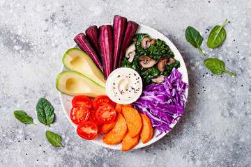 Wall Mural - Buddha bowl with roasted butternut, hummus, shredded red cabbage, tomatoes, avocado, purple carrots, sauteed spinach, mushrooms. Healthy vegetarian appetizer or snack platter. Veggies detox lunch bowl