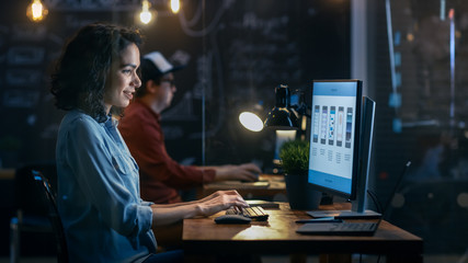 Wall Mural - beautiful female coder works at her desktop on her peropnal computer. her male colleague sits next t