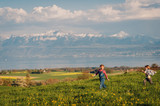 Fototapeta Kuchnia - Two kids, little brother and big sister, playing together outdoors in swiss fields with view on lake Geneva and french mountains Haute-Savoie. Image taken in Lausanne area, canton of Vaud, Switzerland