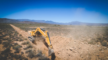 Aerial photo of earth moving machinery front loader digging a trench on a farm