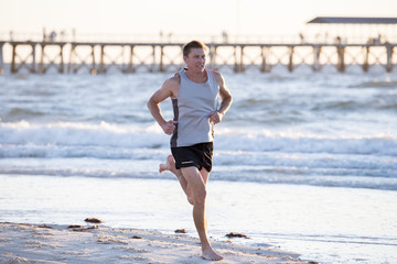 athletic fit and strong runner man training on Summer sunset beach in sea shore running and fitness workout in sport and healthy lifestyle