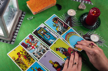 Divination by tarot cards on a background of a green tablecloth with candles.