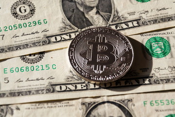 Wall Mural - silver bitcoin coin lying on united states dollars, cryptocurrency concept
