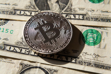 Wall Mural - silver bitcoin coin lying on united states dollars, cryptocurrency concept
