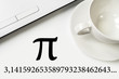 International Pi Day. On a white table a laptop and a cup.
