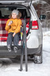 Young girl drinks hot tea after skiing while sitting in trunk of suv car. Winter activity