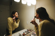 © Cavan Images - Woman applying make-up reflecting on mirror