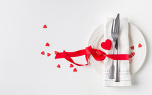 Valentines Day (or Wedding) Meal Background With Red Ribbon, Hearts, Fork, Knife, White Plate And Napkin. Romantic Holiday Table Setting. Beautiful Background With Blank. Restaurant Concept. Flat Lay